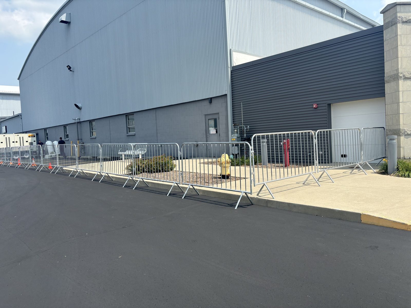 Steel crowd-control barricades along the side of a large metal building