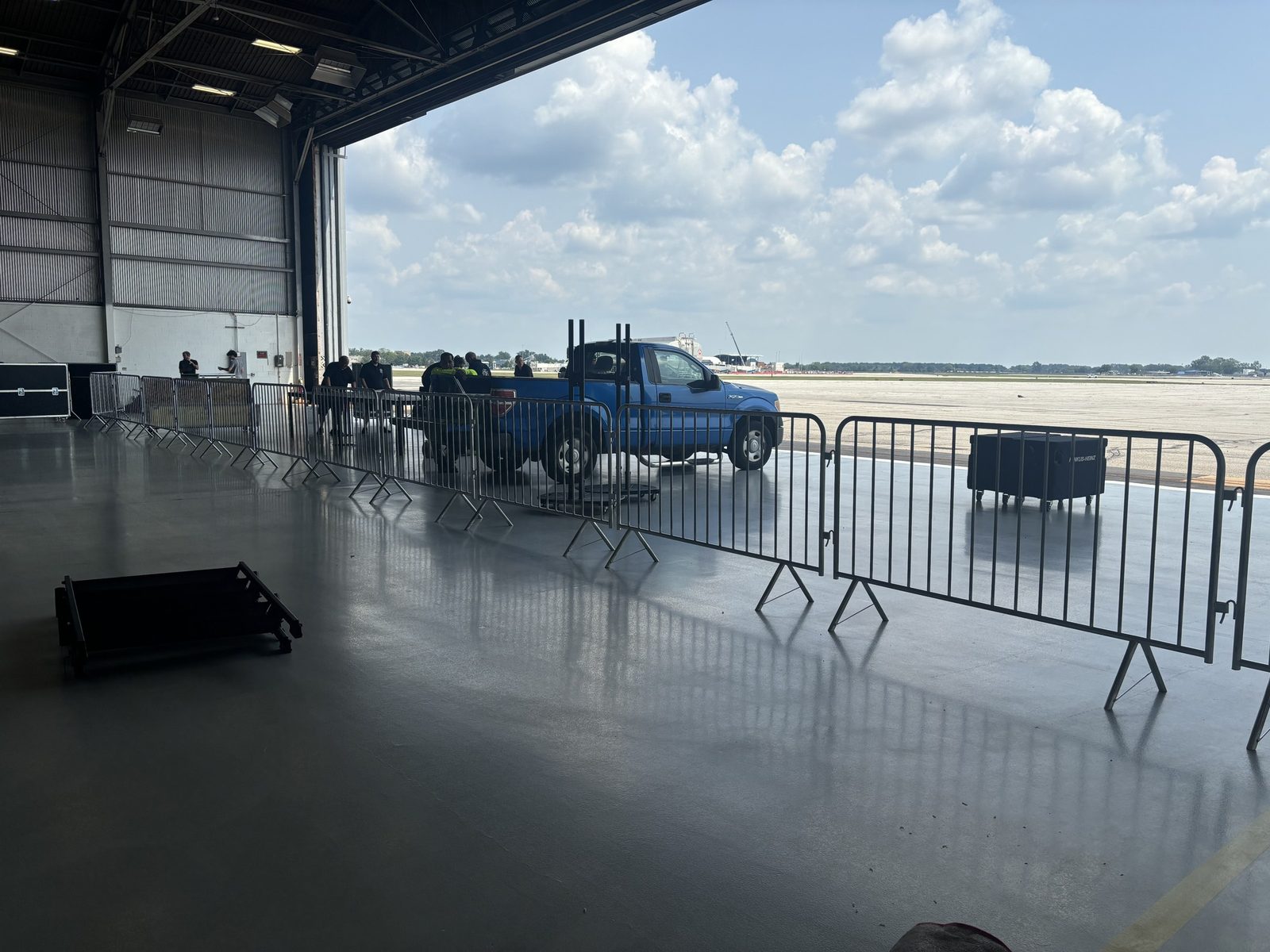 Crowd-control barricades set in a line across the floor of an open hangar