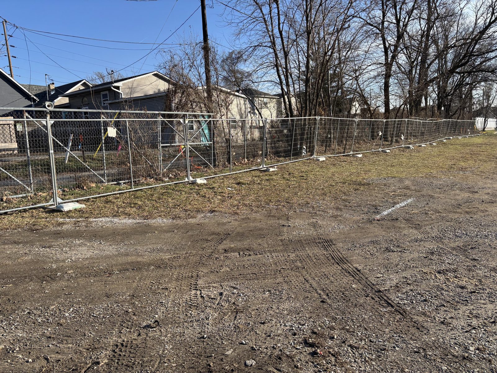Panel fence along a cleared lot next to houses